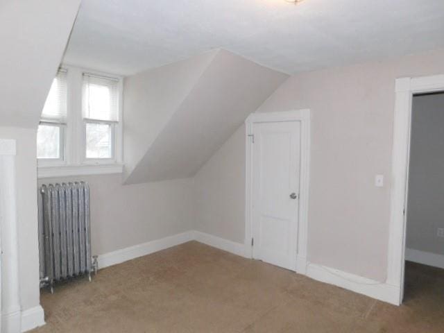 bonus room featuring carpet, radiator heating unit, and lofted ceiling