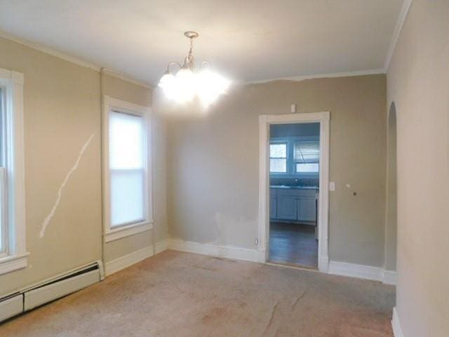 spare room featuring a notable chandelier, carpet floors, crown molding, and a baseboard heating unit