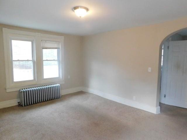 carpeted spare room featuring radiator