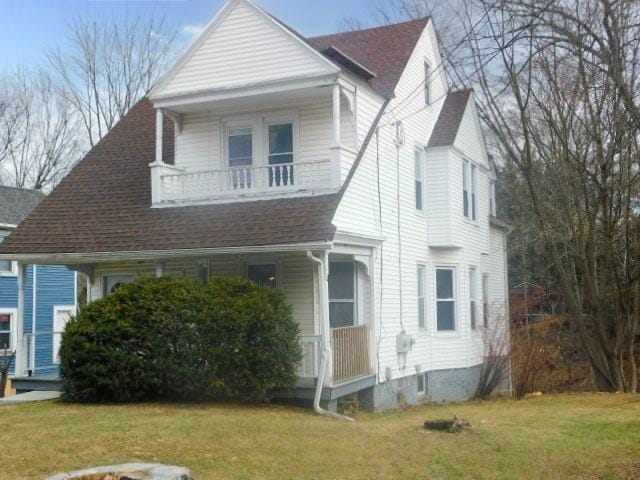 view of front of home with a balcony and a front lawn