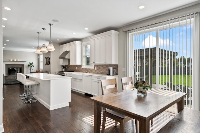 kitchen featuring pendant lighting, a center island, backsplash, sink, and white cabinetry