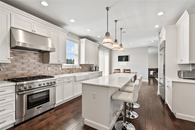 kitchen with pendant lighting, high quality appliances, white cabinetry, and sink