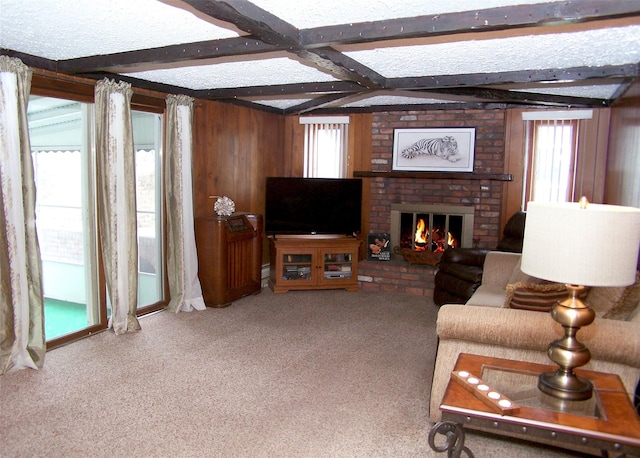 carpeted living room featuring beamed ceiling, a healthy amount of sunlight, and a brick fireplace