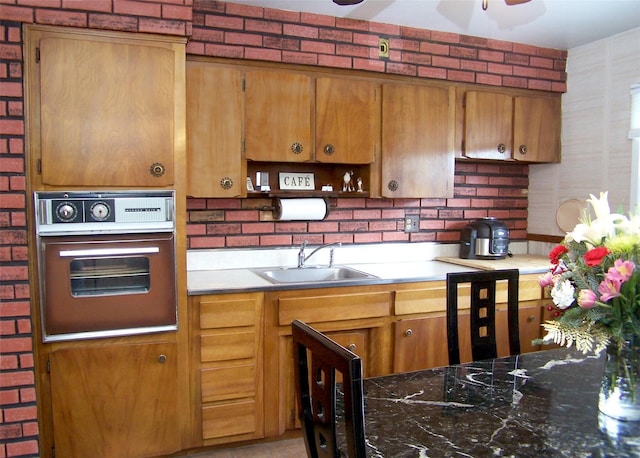 kitchen with oven, sink, and brick wall