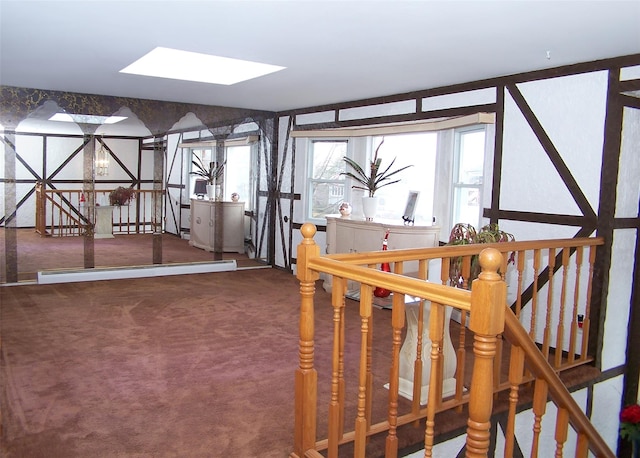 stairway with a skylight, carpet, and a baseboard heating unit