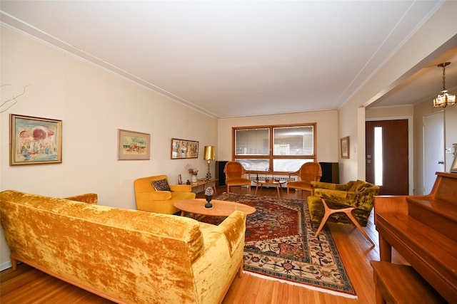 living room with hardwood / wood-style flooring, ornamental molding, and an inviting chandelier