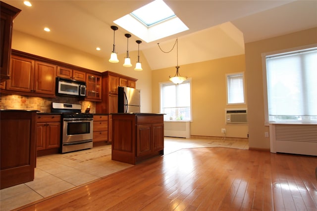 kitchen featuring a center island, backsplash, pendant lighting, vaulted ceiling with skylight, and appliances with stainless steel finishes