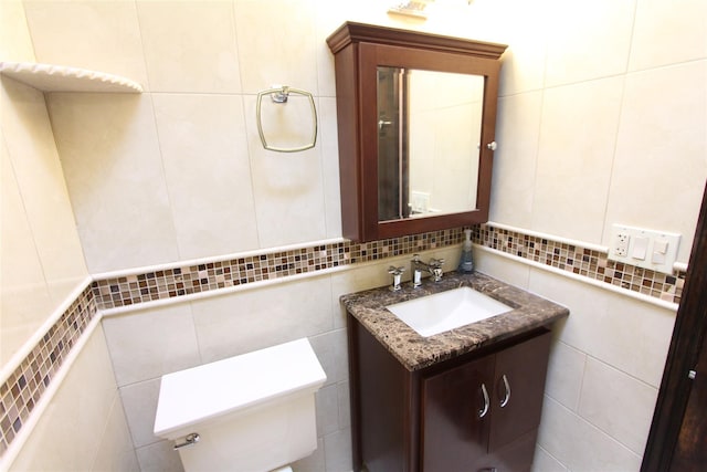 bathroom featuring vanity, toilet, and tile walls