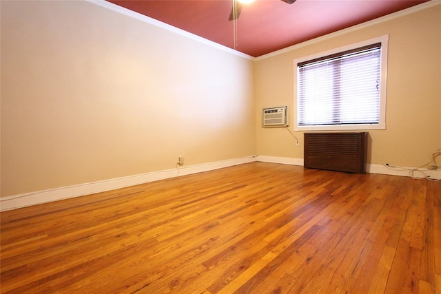 spare room featuring light wood-type flooring, ornamental molding, radiator, and a wall mounted AC