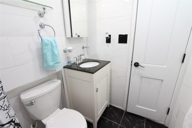 bathroom with vanity, tile walls, and toilet