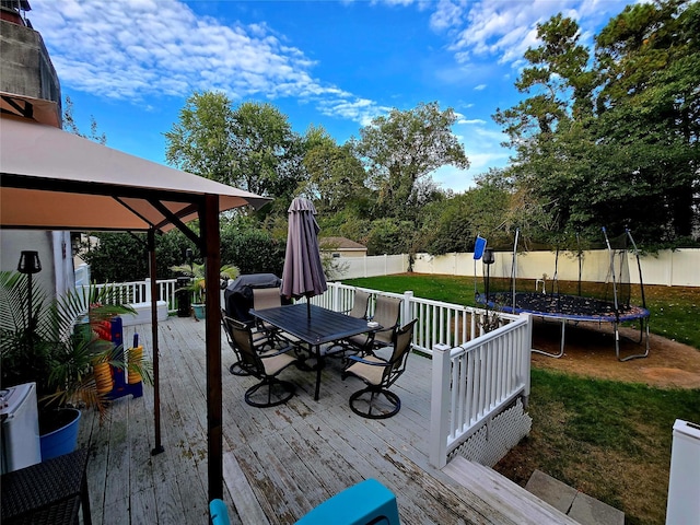 wooden deck with a gazebo, a trampoline, and a lawn