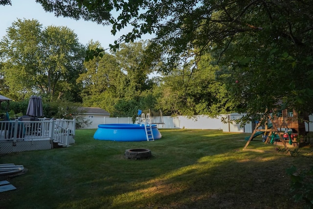 view of yard with a playground, an outdoor fire pit, and a pool side deck