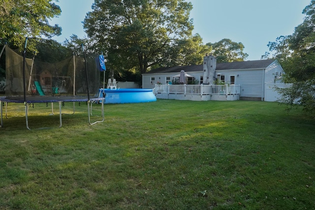 view of yard with a swimming pool side deck and a trampoline