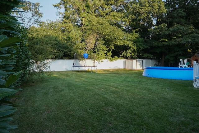 view of yard featuring a fenced in pool, a storage unit, and a trampoline