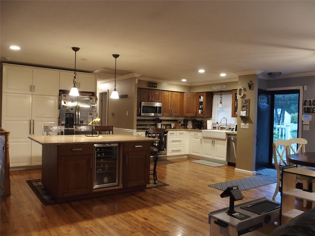 kitchen featuring stainless steel appliances, a kitchen island, sink, pendant lighting, and wine cooler