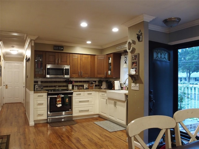 kitchen featuring sink, appliances with stainless steel finishes, tasteful backsplash, white cabinetry, and wood-type flooring