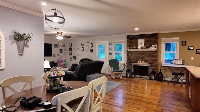 dining area featuring ceiling fan, crown molding, light wood-type flooring, and a fireplace