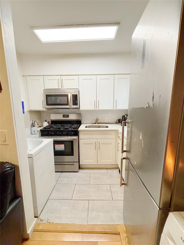 kitchen with sink, white cabinets, light tile patterned floors, and appliances with stainless steel finishes