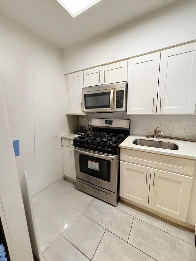 kitchen featuring white cabinets, sink, light tile patterned floors, tasteful backsplash, and stainless steel appliances