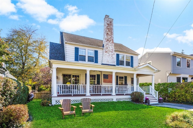 view of front of home featuring covered porch, roof with shingles, a front yard, and a chimney