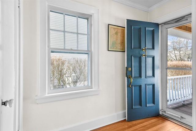 foyer entrance with ornamental molding, wood finished floors, and baseboards