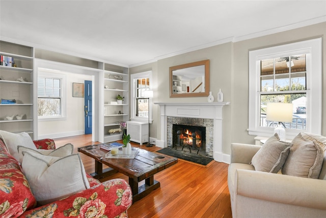 living room featuring plenty of natural light, wood finished floors, and a lit fireplace