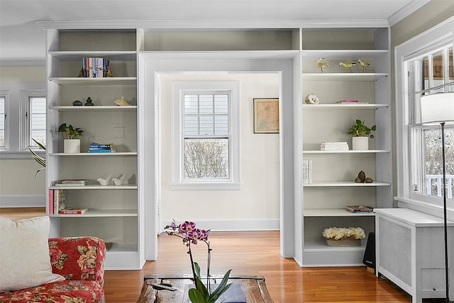 interior space featuring built in features, crown molding, baseboards, and wood finished floors