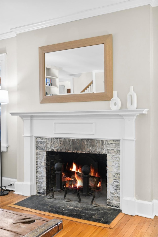 room details with baseboards, wood finished floors, a fireplace with flush hearth, and crown molding