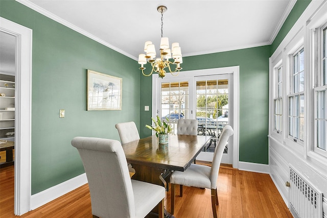 dining space featuring a notable chandelier, crown molding, radiator heating unit, and wood finished floors