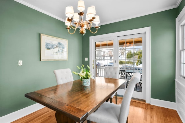 dining room with crown molding, baseboards, and light wood-style floors