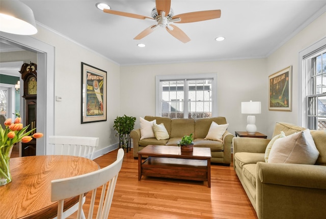 living area featuring light wood-style floors, recessed lighting, a healthy amount of sunlight, and crown molding