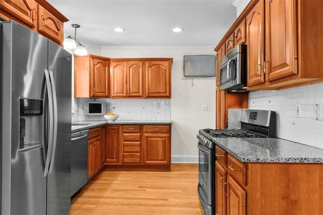 kitchen with dark stone counters, stainless steel appliances, brown cabinetry, and pendant lighting