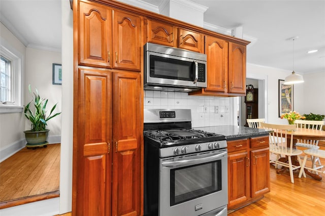 kitchen with stainless steel appliances, crown molding, light wood-type flooring, pendant lighting, and backsplash