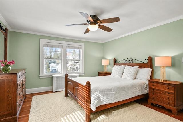 bedroom with baseboards, a ceiling fan, radiator heating unit, wood finished floors, and crown molding