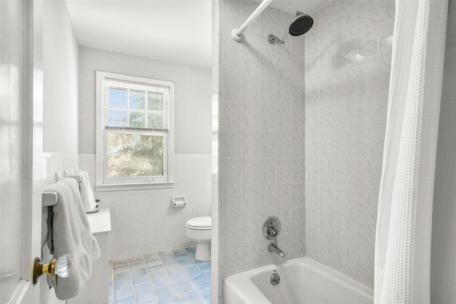 full bathroom with tile patterned flooring, toilet, tile walls, wainscoting, and shower / tub combo with curtain