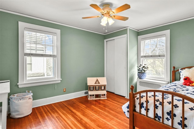 bedroom featuring ceiling fan, baseboards, light wood-style floors, a closet, and crown molding