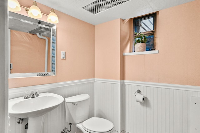 bathroom featuring wainscoting, a sink, and toilet