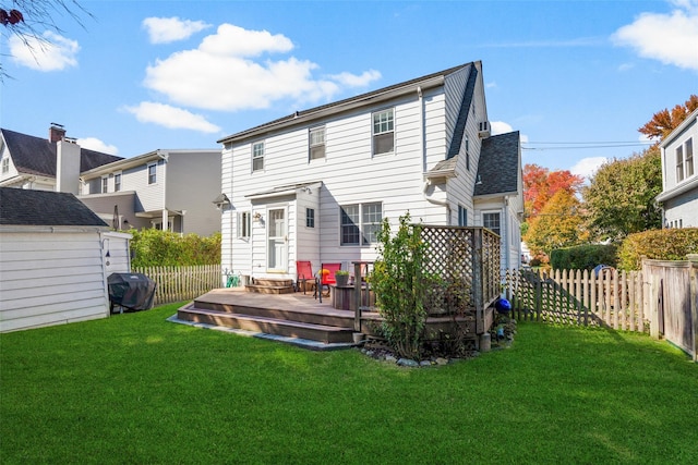 rear view of property featuring a fenced backyard, an outdoor structure, a lawn, a wooden deck, and a storage unit