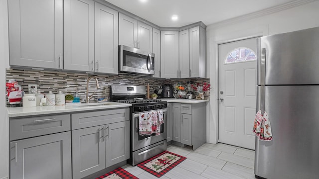 kitchen featuring backsplash, gray cabinetry, sink, and appliances with stainless steel finishes