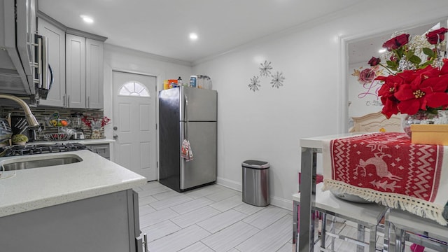 kitchen featuring gray cabinetry, sink, stainless steel fridge, ornamental molding, and tasteful backsplash