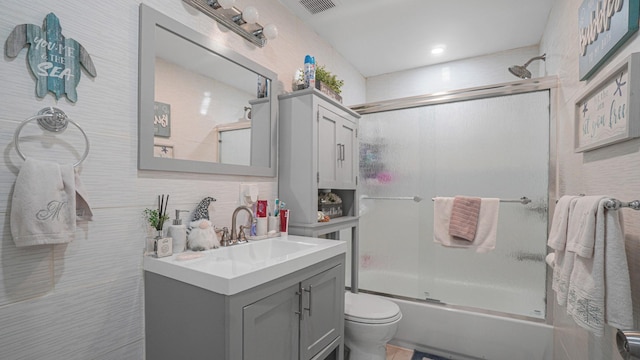 full bathroom featuring shower / bath combination with glass door, backsplash, vanity, and toilet