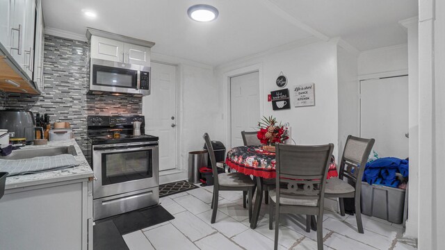2354 Waterbury Ave, Bronx, NY 10462 - kitchen with appliances with stainless steel finishes, backsplash, light countertops, ornamental molding, and white cabinets