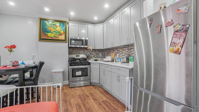 kitchen with tasteful backsplash, gray cabinets, light hardwood / wood-style flooring, and stainless steel appliances