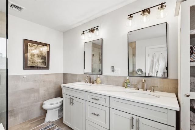 bathroom featuring tile patterned flooring, vanity, tile walls, and toilet