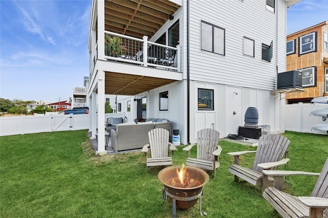 back of property with a lawn and an outdoor living space with a fire pit