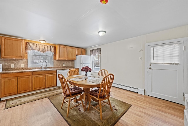 dining area with a healthy amount of sunlight, light hardwood / wood-style floors, baseboard heating, and sink