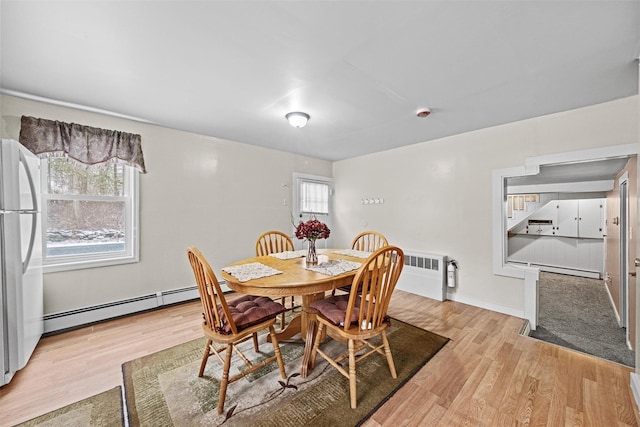 dining space featuring plenty of natural light, baseboard heating, and light hardwood / wood-style flooring