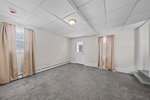 carpeted empty room with a paneled ceiling and baseboard heating