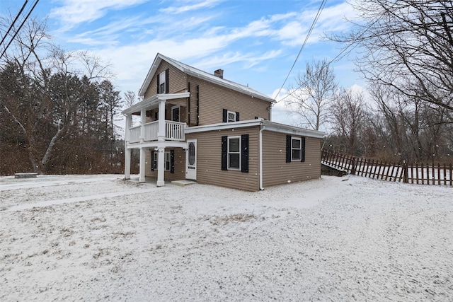 snow covered property with a porch and a balcony