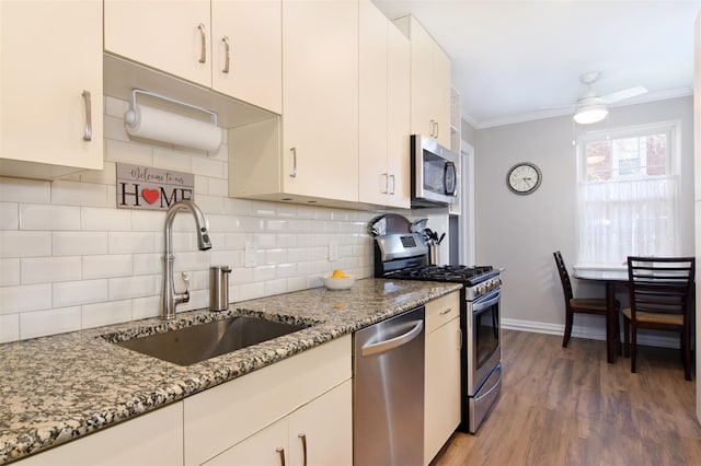 kitchen with backsplash, sink, ceiling fan, light stone counters, and stainless steel appliances